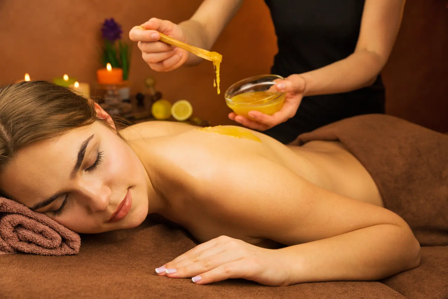 Schöne Frau im Spa-Salon bei einer Spa-Therapie-Honigbehandlung mit den Händen eines Masseurs